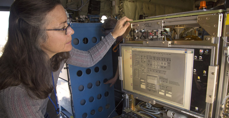 Woman scientist checks observing equipment aboard an NCAR research aircraft
