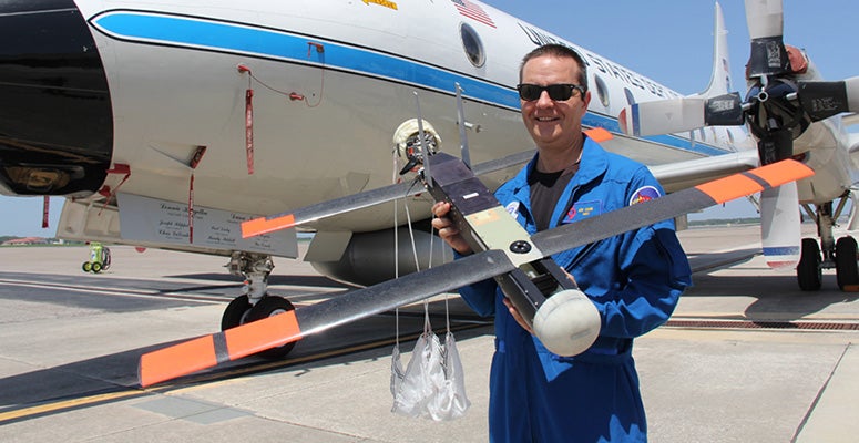 NOAA scientist Joe Cione, lead author of a new paper on using disposable drones for hurricane observations, holds a Coyote drone in front of a NOAA P-3 "hurricane hunter" research aircraft at McDill Air Force Base in Tampa, Fla.