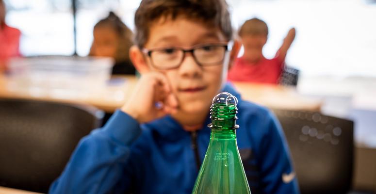 A young student does a science experiment with a soda bottle