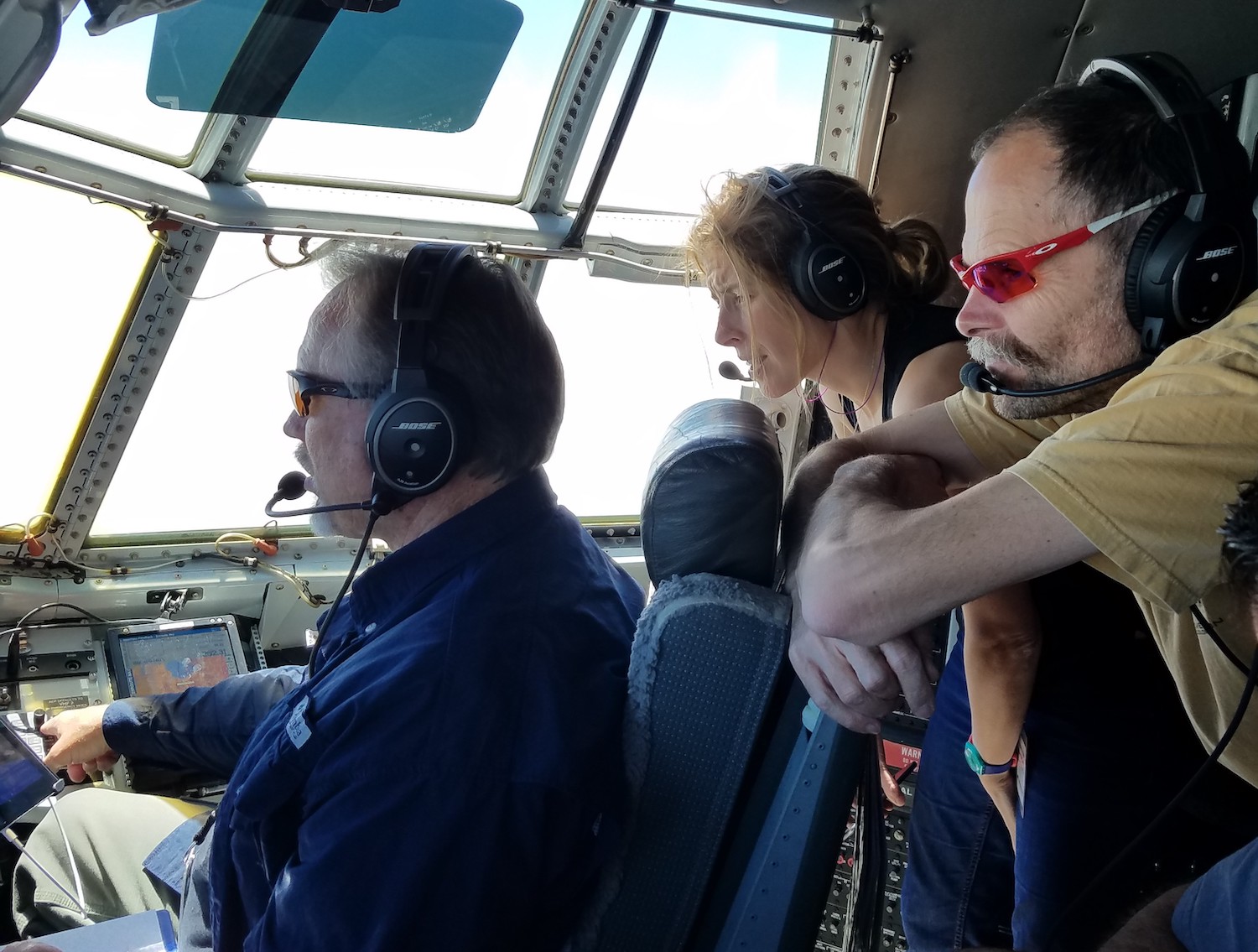 Scientists talking with the pilot in the cockpit of a research aircraft during a research mission to study wildfire smoke