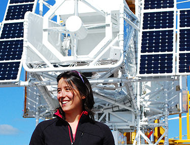 Image of Rebecca Centeno Elliott, and a satellite with solar panels behind her. 