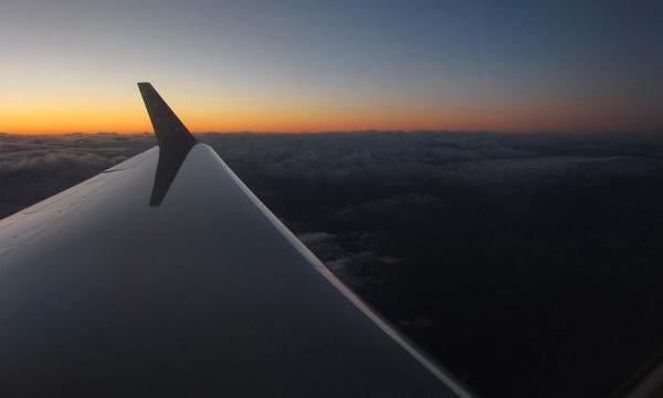 Looking down the wing of a plane during flight over Antarctica at sunset