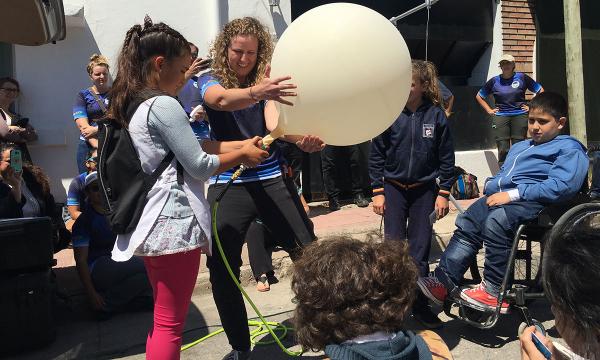 Un científico trabaja con jóvenes estudiantes en Argentina para preparar un globo meteorológico para su lanzamiento.