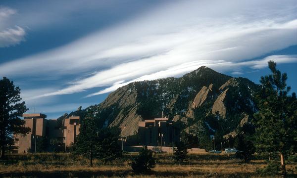 A tan building set in front of mountains and clouds