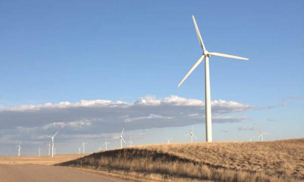 Windmills on a grassy hill with a blue sky and clouds