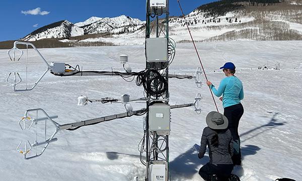 NCAR scientist Jacqueline Witte (kneeling) and software engineer Isabel Suhr (standing) measure the distance between sonic anemometer arms on an Integrated Surface Flux System (ISFS) weather tower.